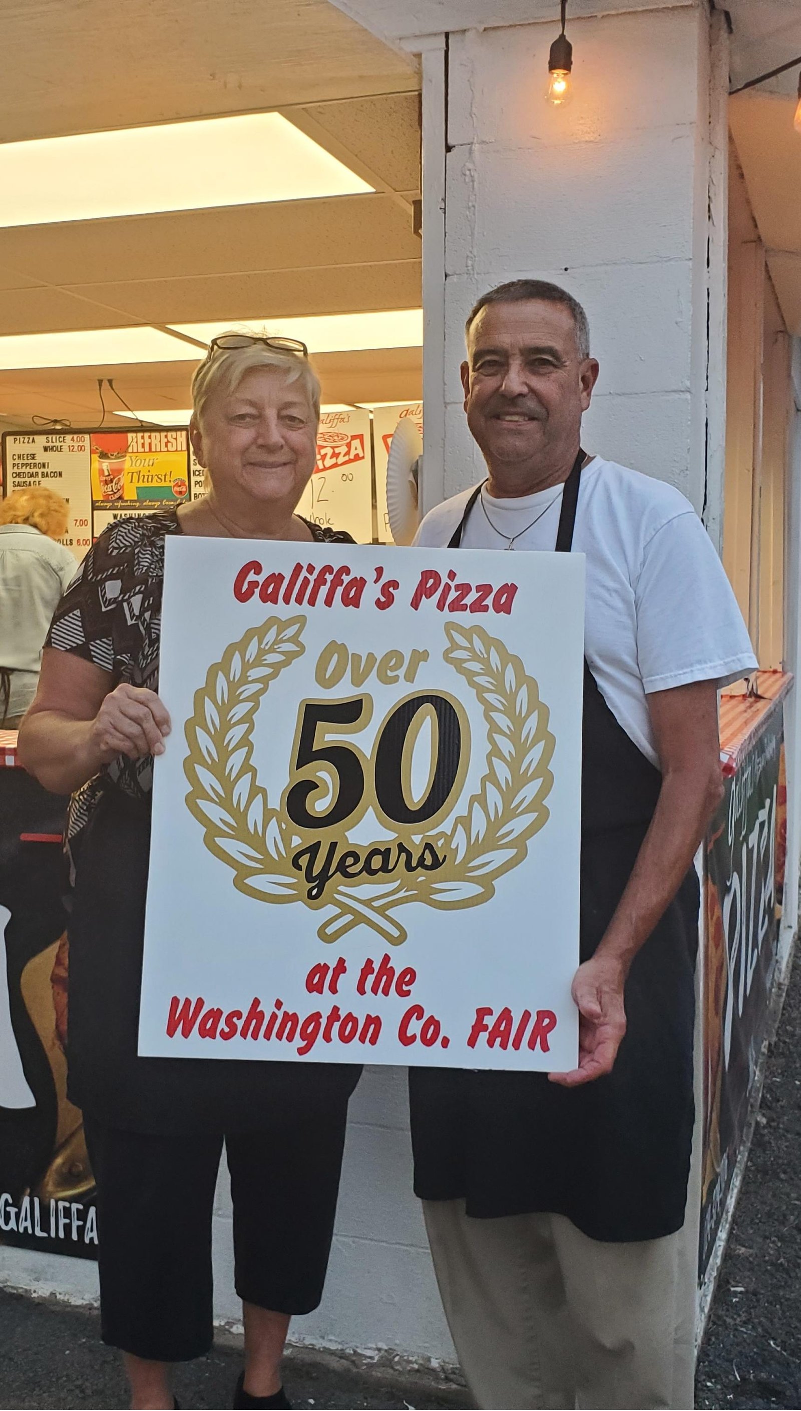 Barry and Judy Galiffa holding a sign celebrating over 50 years at the Washington County Fair